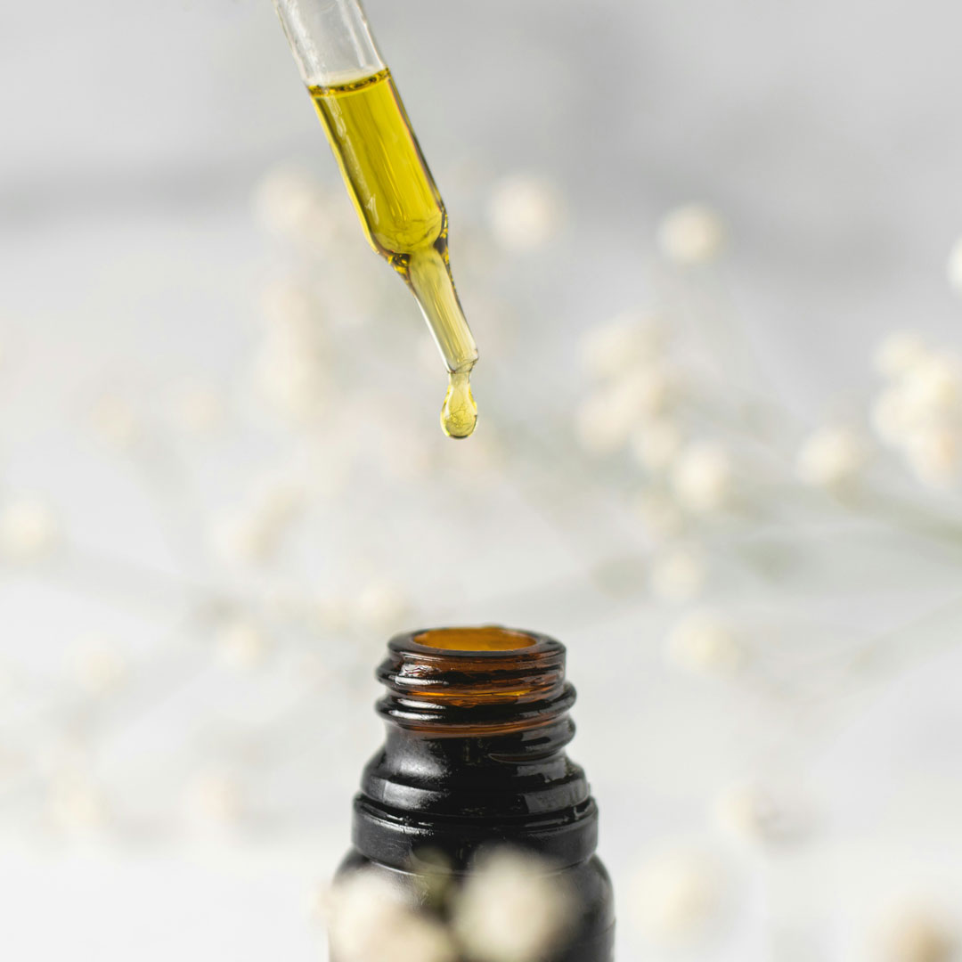 Kapaljka sa žutom tekućinom, CBD uljem, ispušta kapljicu "zlatnog" ulja u bočicu